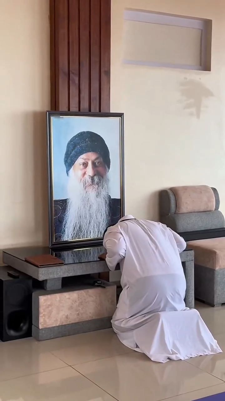 A disciple bowing in reverence before Osho portrait